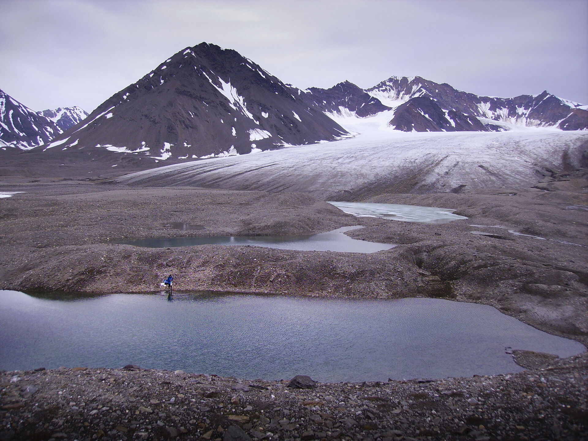 Moraine lakes at the foot of a glacier in the Ny-&Aring;lesund area of Svalbard. A researcher is preparing to take zooplankton samples in the pond furthest downstream.